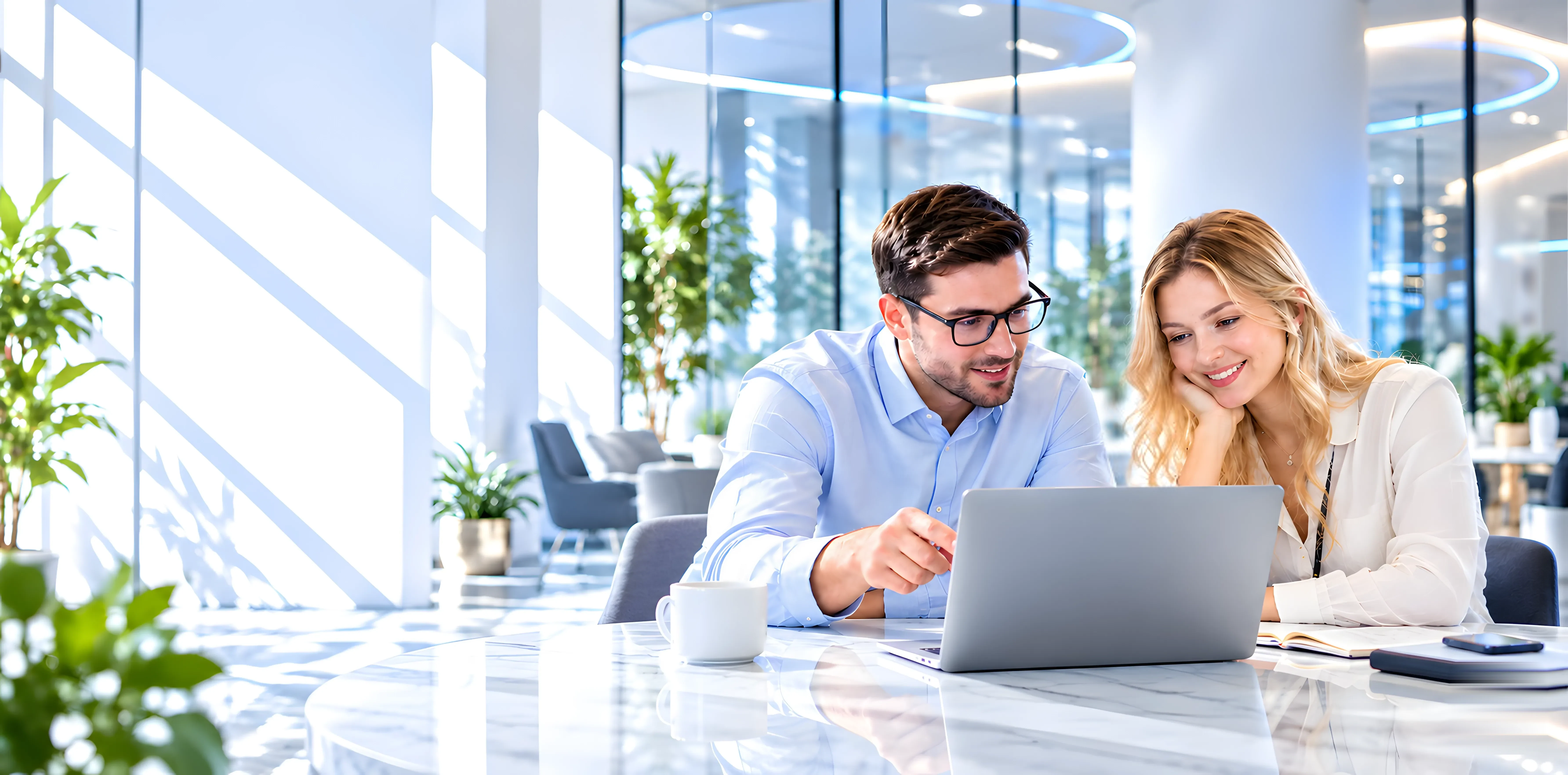 Two colleagues reviewing a laptop together in a bright modern office.